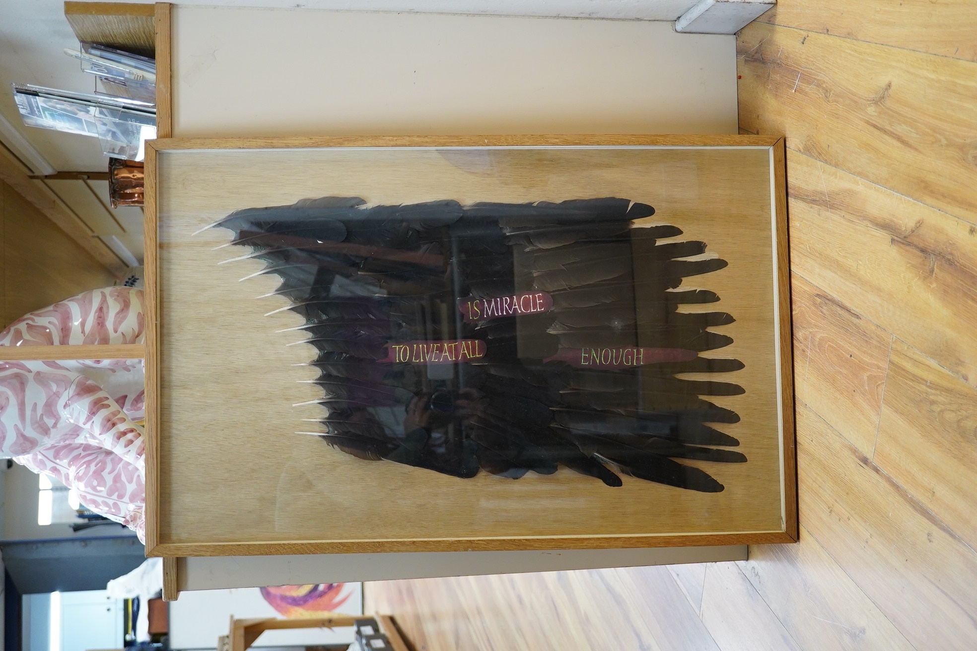 A framed American feather appliqué with message “To Live At All Is A Miracle Enough”, 84cm high, 53wide. Condition - good